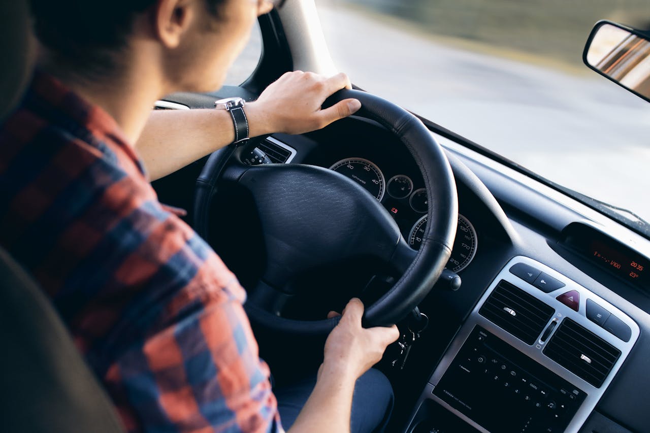 about-04 Close-up view of a man driving a modern car, showing dashboard and steering details.